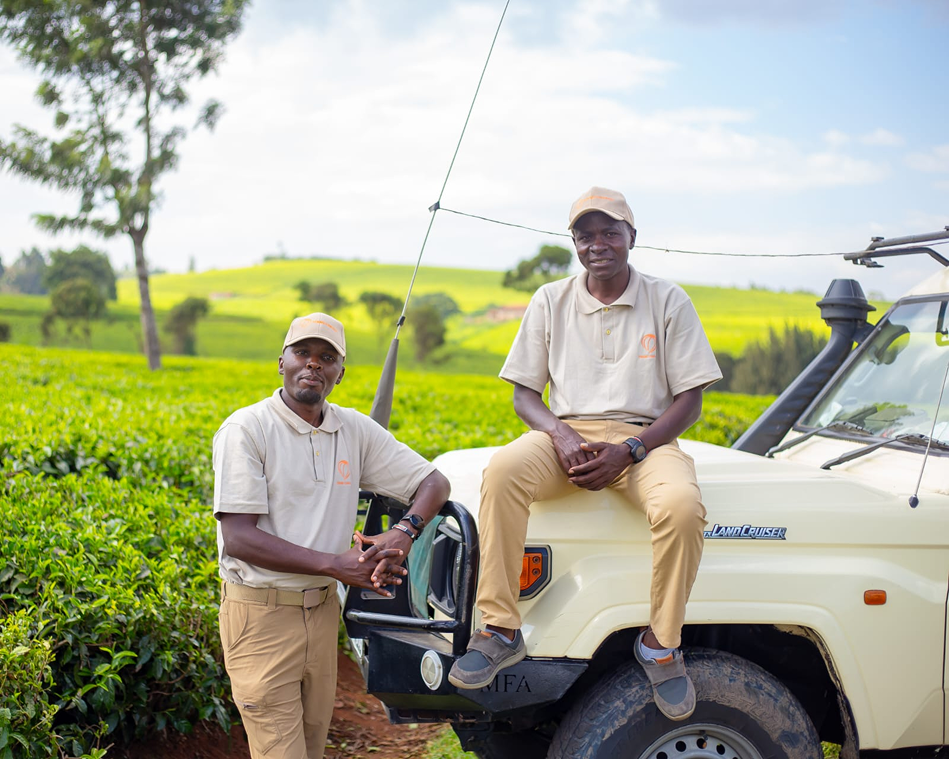 Two men posing with a white vehicle in a green field.