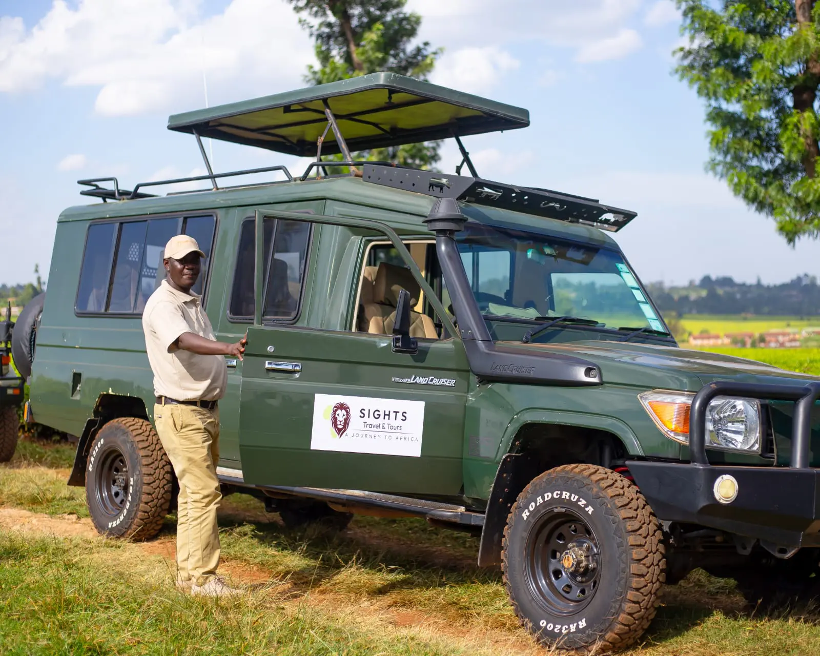 Game ranger standing next to a safari vehicle with tourists inside.